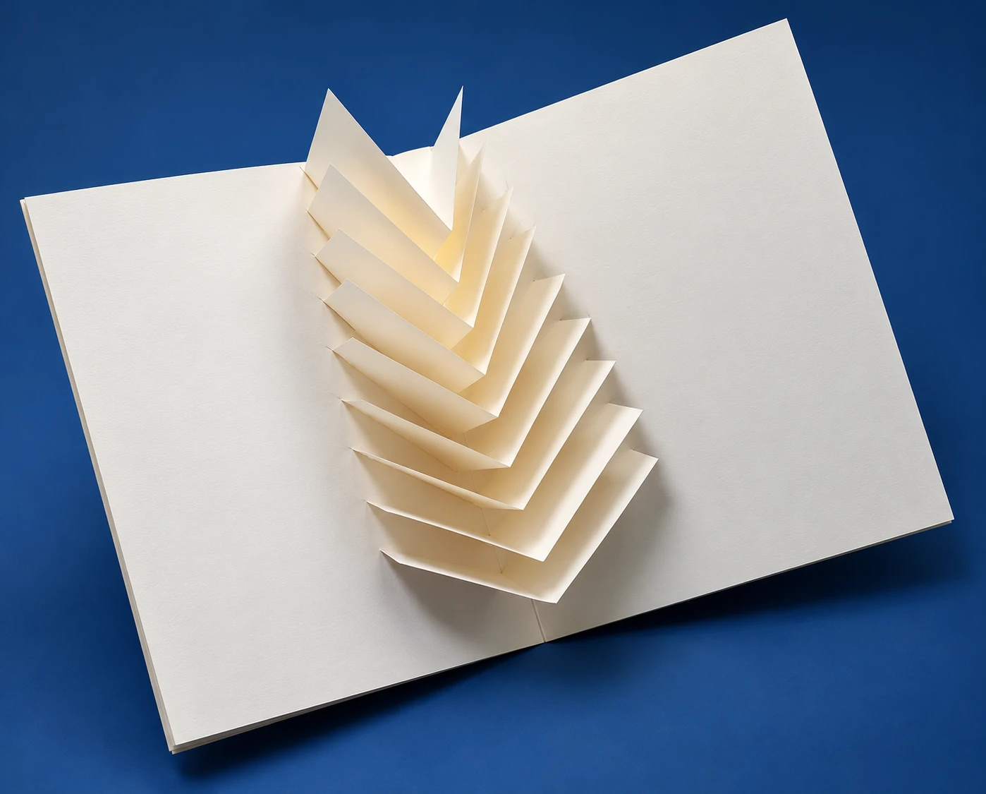 Libro pop-up de papel blanco abierto sobre fondo azul – Dario Zeruto