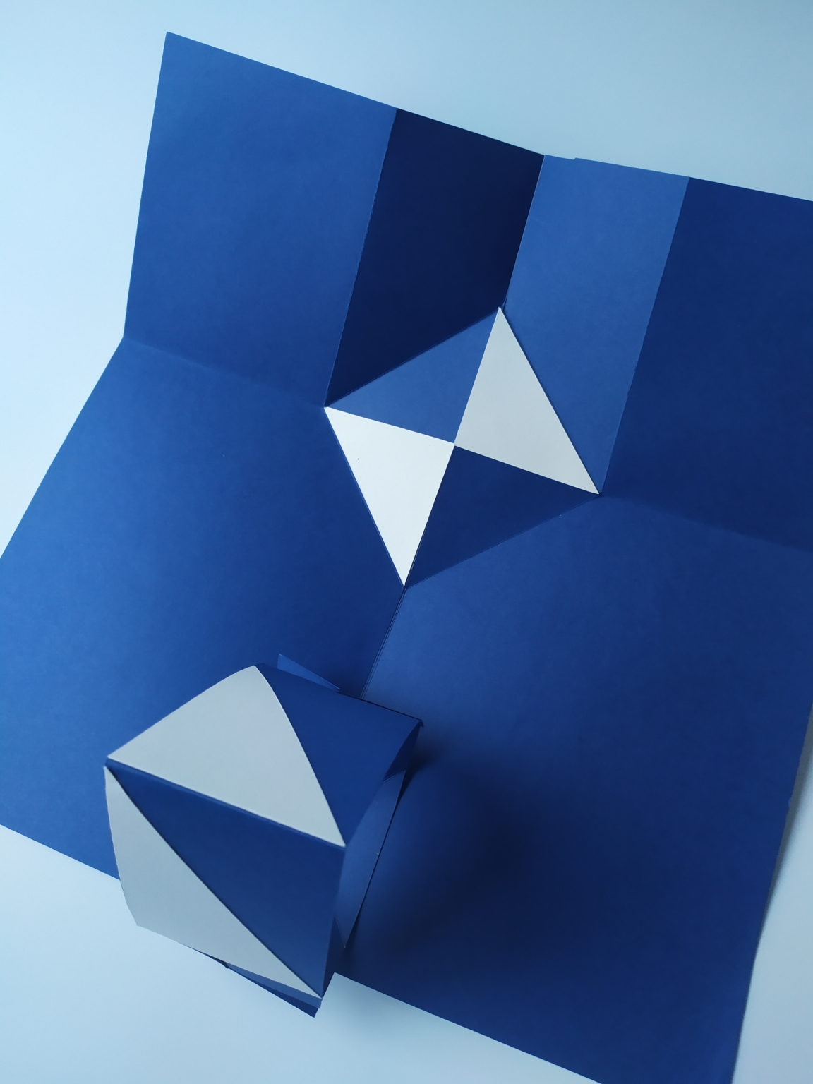 Estructura de pliegue y corte en papel azul y blanco – Dario Zeruto